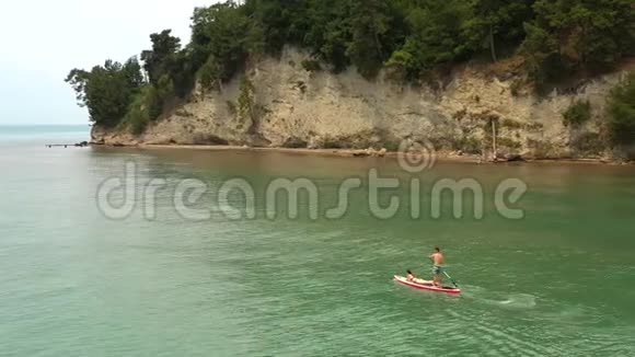 一对年轻夫妇沿着海岸线漂浮在惊人的绿色悬崖上视频的预览图