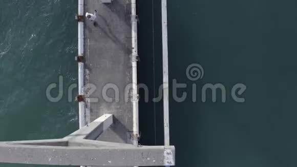 高空观景人在蓝色海面上的桥上奔跑年轻人跑码头海滩视频的预览图