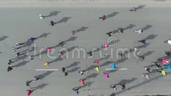 在城市道路上的马拉松比赛中一群跑步者的高空向下拍摄视频的预览图
