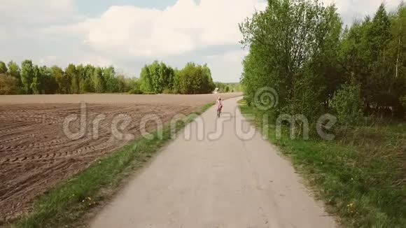 穿着衣服的女农民在路上骑自行车视频的预览图