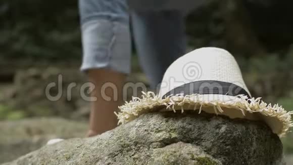 女人拿起草帽走过岩石视频的预览图