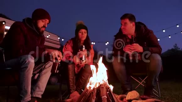 白种人留胡子的人在野营火边给朋友讲故事视频的预览图