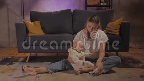 一个女人和她的孩子在一个舒适的公寓里靠近沙发的地板上玩耍妈妈和宝贝都很开心视频的预览图