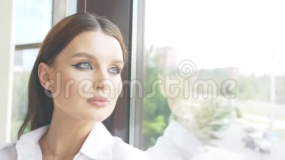 一个女人透过窗户看着城市的街道她的脸映在玻璃上视频的预览图