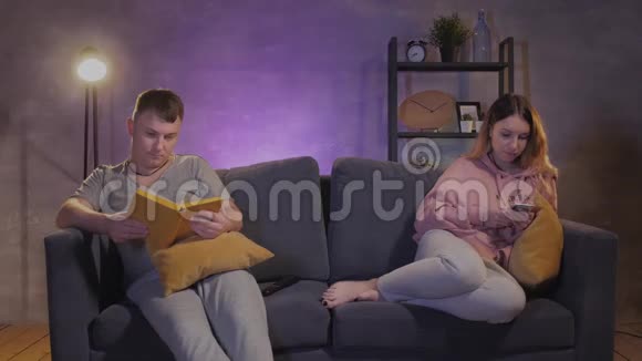 一男一女坐在舒适的房间里的沙发上写着电话女孩在看书视频的预览图