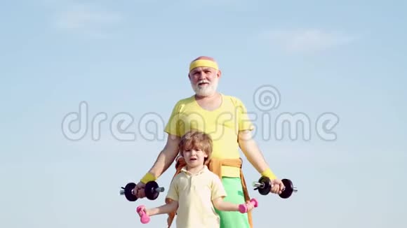 祖父和孩子举起哑铃健康生活和运动理念帮孩子锻炼身体的爷爷视频的预览图