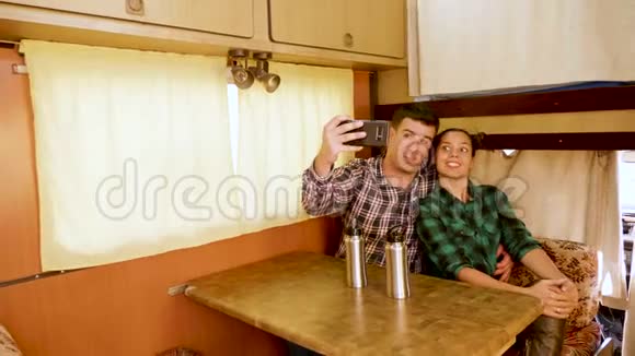 漂亮的年轻夫妇在复古露营车里自拍视频的预览图