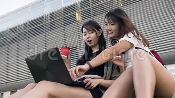 两个漂亮的亚洲棕发女郎坐在草地上用电脑在草地上她的肖像很有吸引力视频的预览图