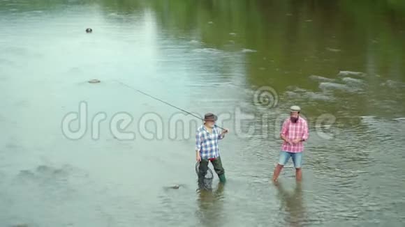 父亲和儿子在兴飞鱼在美丽的河流中使用飞鱼竿家庭和世代暑假视频的预览图