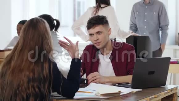 专业年轻的男性人力资源经理听女同事说话面试时坐在办公室桌子上视频的预览图