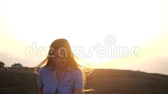 快乐的年轻女性女孩在阳光明媚的日落背景下奔跑她那丝质的长发在风中飘扬她微笑着视频的预览图