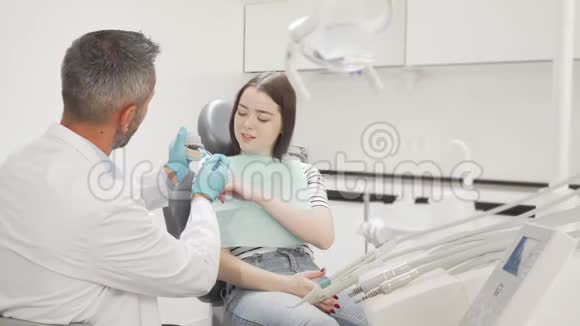 可爱的年轻女子从她的牙医那里学习牙科护理视频的预览图