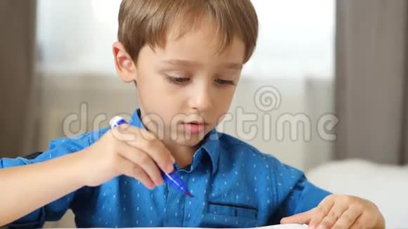 一个小男孩坐在桌子旁给一个幸福的家庭画一支明亮的毛尖笔儿童创造力的发展视频的预览图