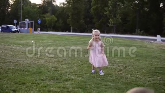 快乐的妈妈长着长长的金发一边笑着一边慢吞吞地驮着她的小女孩绿色公园视频的预览图