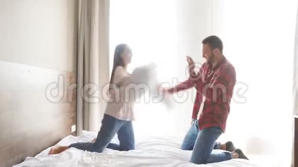 年轻的一家人在家里玩枕头的卧室笑容满面视频的预览图