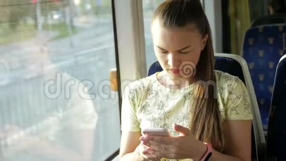 一幅迷人的严肃女孩在火车上使用智能手机与朋友聊天的肖像慢动作视频的预览图