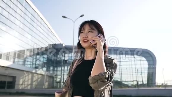 美丽的肖像吸引人的年轻的亚洲黑发长发在机场大楼附近的电话交谈视频的预览图
