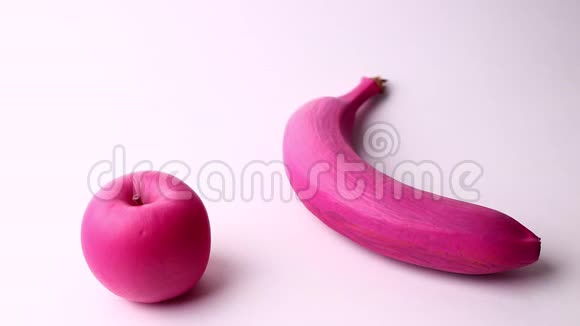 粉红色香蕉和粉红色苹果分离在白色背景上演播室拍摄全高清视频的预览图