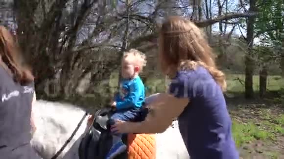 小男孩孩子骑小马妈妈照顾他的安全万向节运动视频的预览图