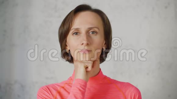肖像成年女子抱着下巴的拳头看着镜头布鲁内特女士在白人身上做面部模拟体操视频的预览图
