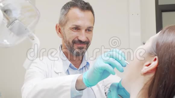 有经验的男性牙医在检查病人牙齿时微笑视频的预览图