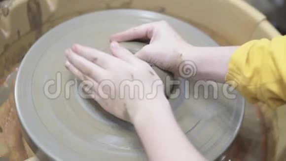 一个男孩在陶工的轮子上做一杯黏土视频的预览图