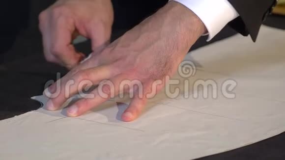 一个裁缝在把它切割成进一步加工的部分之前在织物上画出最后的线条视频的预览图