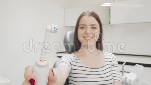有选择地专注于幸福女人手中的电动牙刷视频的预览图