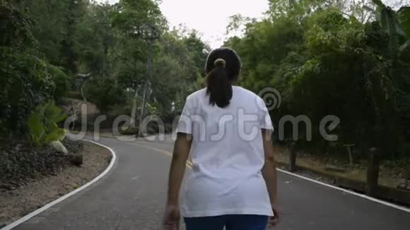 亚洲女人在路上穿过小山从女性的后方观看瞄准山视频的预览图