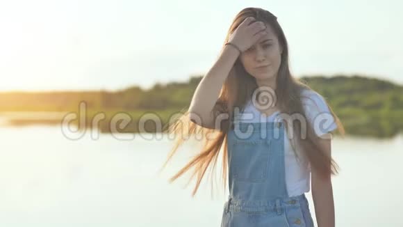 湖背景上一个穿着工作服的17岁棕色头发女孩的肖像视频的预览图