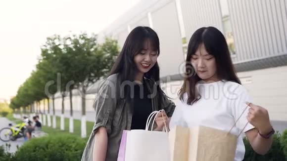 迷人的年轻亚洲女性在户外购物后修改购买视频的预览图