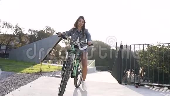 年轻时尚的白人女孩穿着时尚牛仔裤骑着自行车在特别装备的地方骑自行车视频的预览图