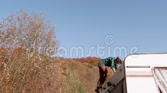 一位美丽的白种人年轻女士从她的露营车顶下来视频的预览图