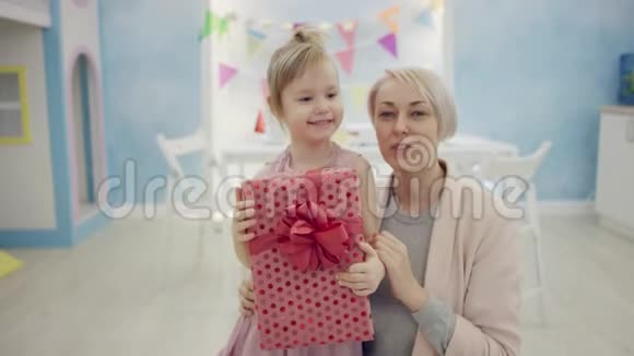 妈妈和小女儿拿着生日礼物坐在镜头前微笑着竖起大拇指视频的预览图