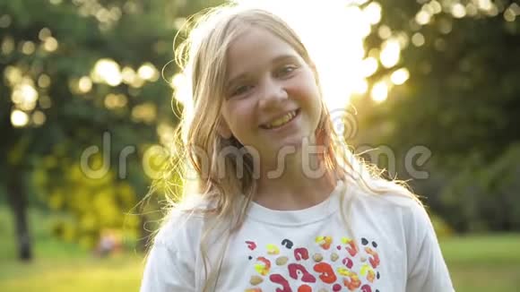 美丽的微笑少年金发女孩对抗绿色的夏季公园小男孩有很多有趣的时间视频的预览图