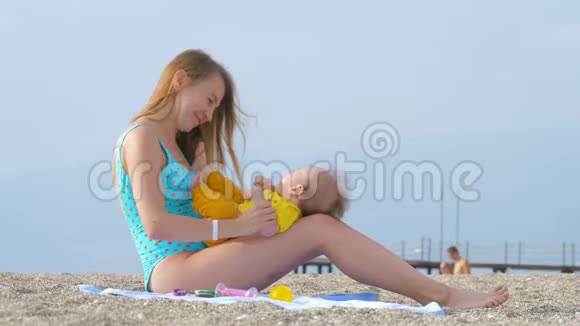 一位年轻的母亲在沙滩上和她的孩子玩耍视频的预览图