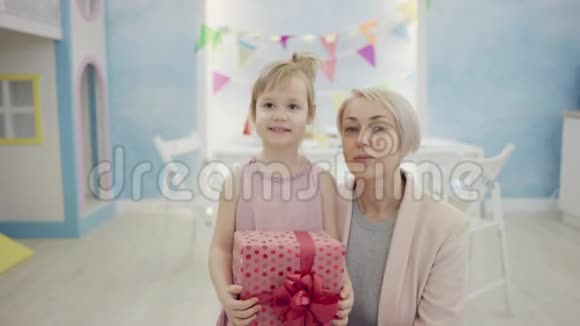 成年女子抱着小女儿手里拿着生日礼物在镜头前和她说话视频的预览图