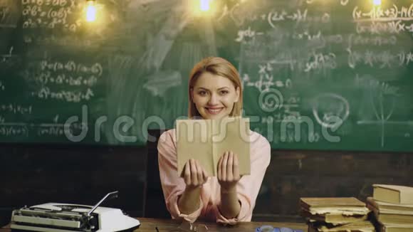 女人微笑着女老师手里拿着书在绿色的学校董事会背景上微笑学校背景视频的预览图