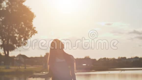 长头发的女孩心情很好在一个温暖的夏天晚上在湖边视频的预览图