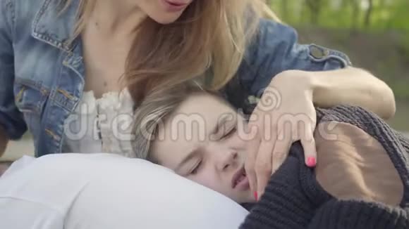 肖像可爱的男孩睡在妈妈手里女人在公园里抚摸她孩子的头发户外休闲视频的预览图
