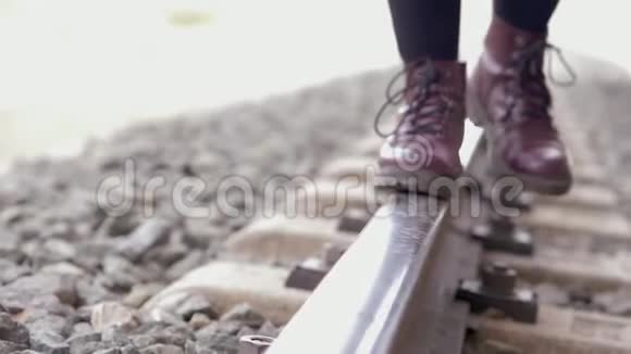 带着紫色靴子的年轻女子走在火车轨道上慢动作视频的预览图