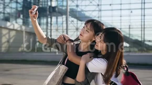 两位最好的朋友亚洲女孩用真诚的微笑在机场大楼上自拍的漂亮肖像视频的预览图