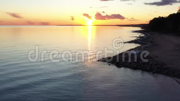 Dron日落时分飞越海岸风景如画的日落宁静的水沙滩树梢视频的预览图