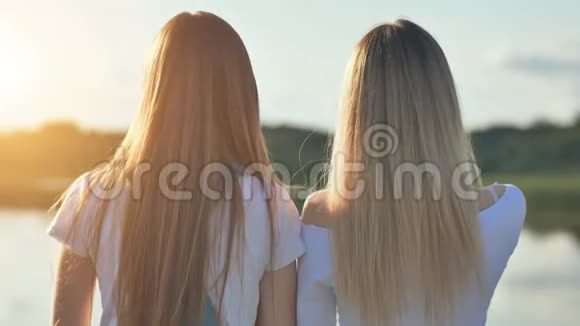 两个金发女孩站在温暖的阳光明媚的夜晚视频的预览图