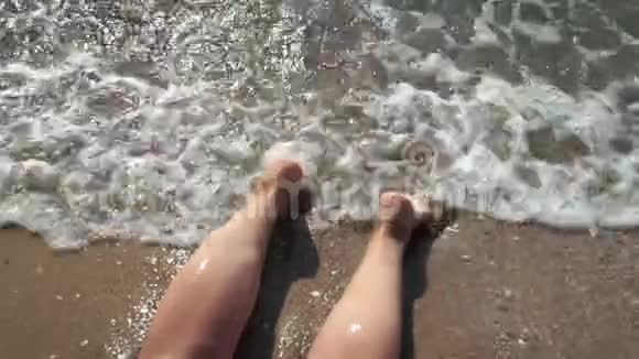 海水冲刷着晒黑的雌性脚美丽的年轻女子在暑假期间在海岸放松视频的预览图