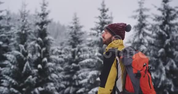 在一个寒冷的冬天他戴着一顶红帽子在雪地森林中他感到快乐和热情的游客兴奋视频的预览图