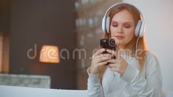 年轻快乐的女人在沙发上听音乐年轻快乐迷人的女人在沙发上听音乐视频的预览图