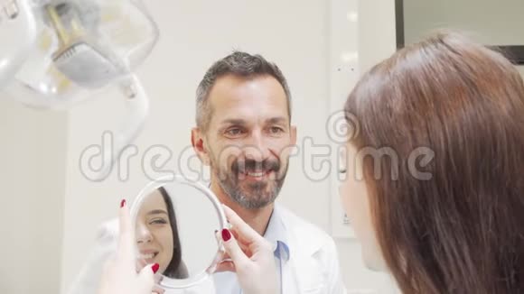 快乐成熟的牙医在体检后与病人交谈视频的预览图