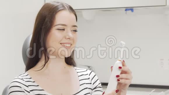 漂亮的女人在检查电动牙刷视频的预览图