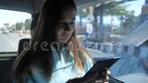年轻女子乘公共汽车旅行看电子书女孩在车窗前的车里旅行视频的预览图